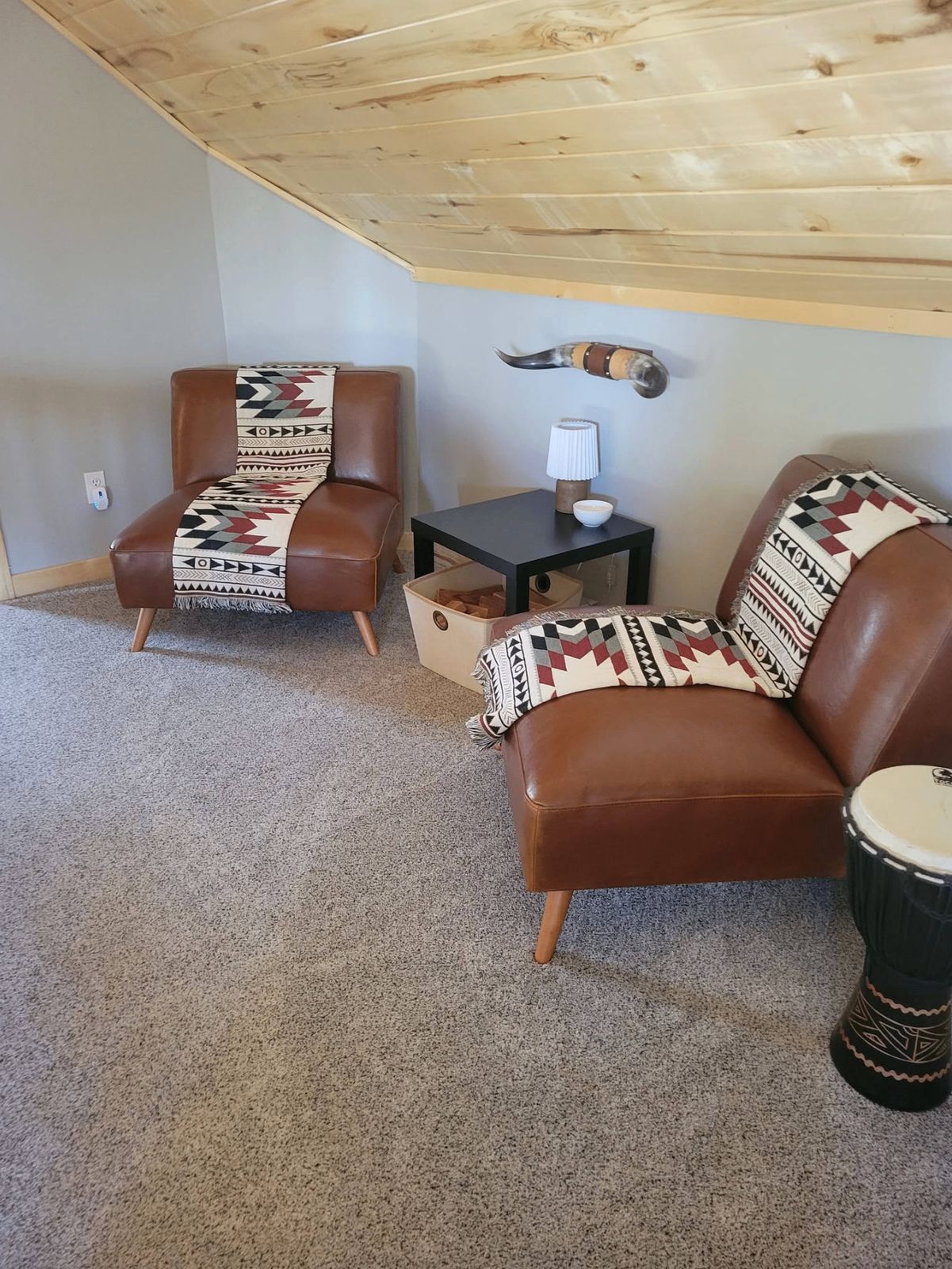Upstairs lounge with leather chairs, throw pillows, and vaulted pine ceiling