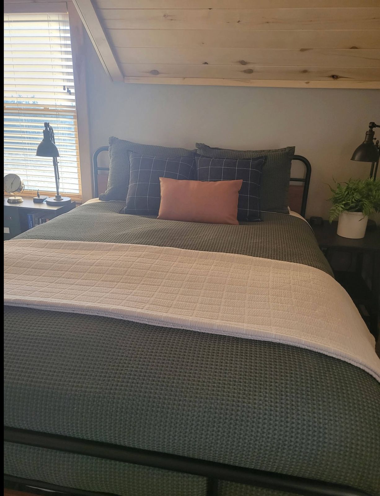 Freshly made queen bed with layered linens and cabin nightstands